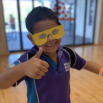 Young student wearing simulation glasses smiling at the camera giving a thumbs up